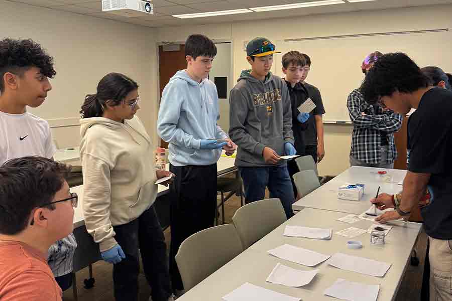 A group of teenagers learning about fingerprinting in a Super Saturday class