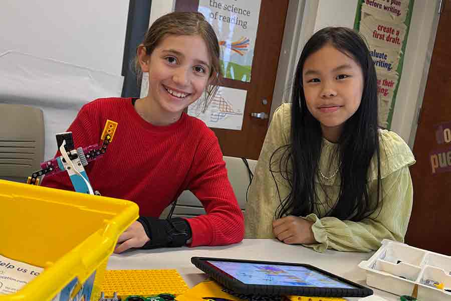 Two middle grades girls with a robotics kit at a Super Saturday event