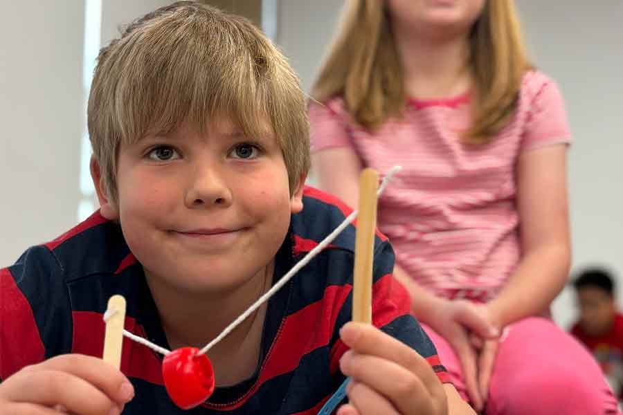 Close up of a young boy holding a contraption he made in a class about designing playgrounds