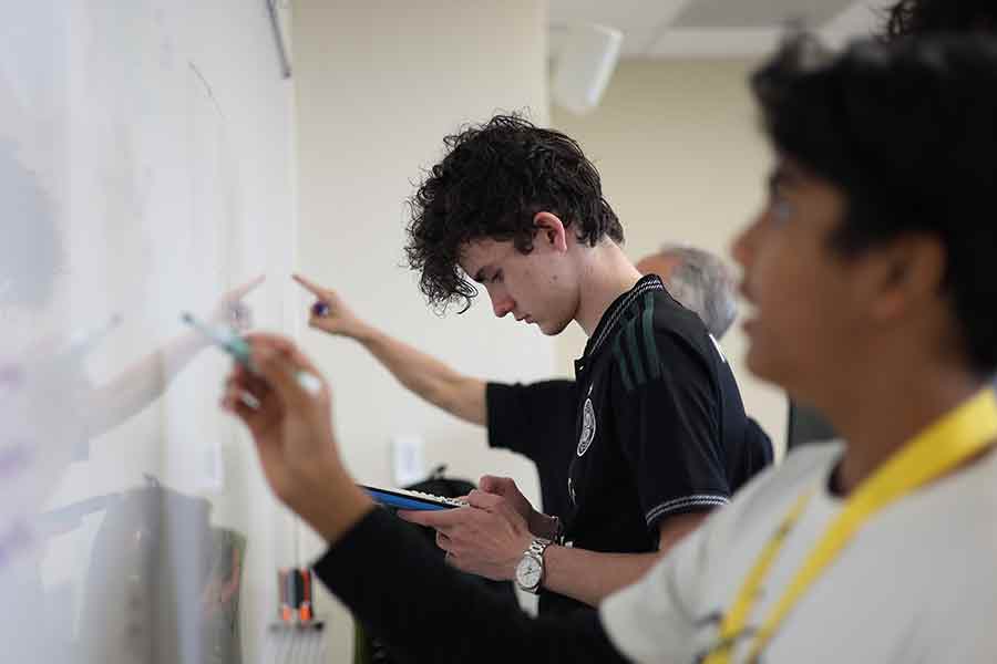 TIP Academy student at the whiteboard with a calculator