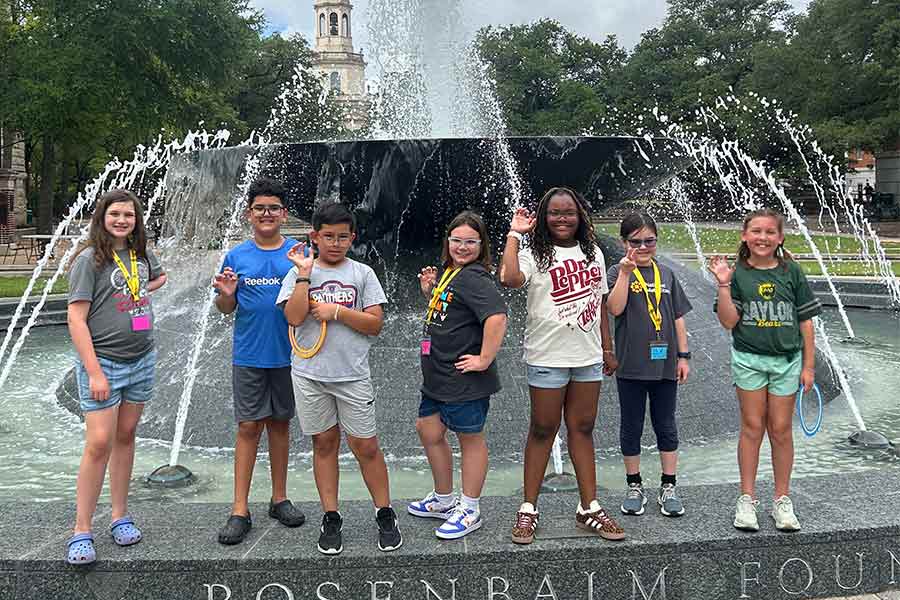 Seven middle grades students standing in front of the Rosenbalm Fountain giving a sic 'em bears