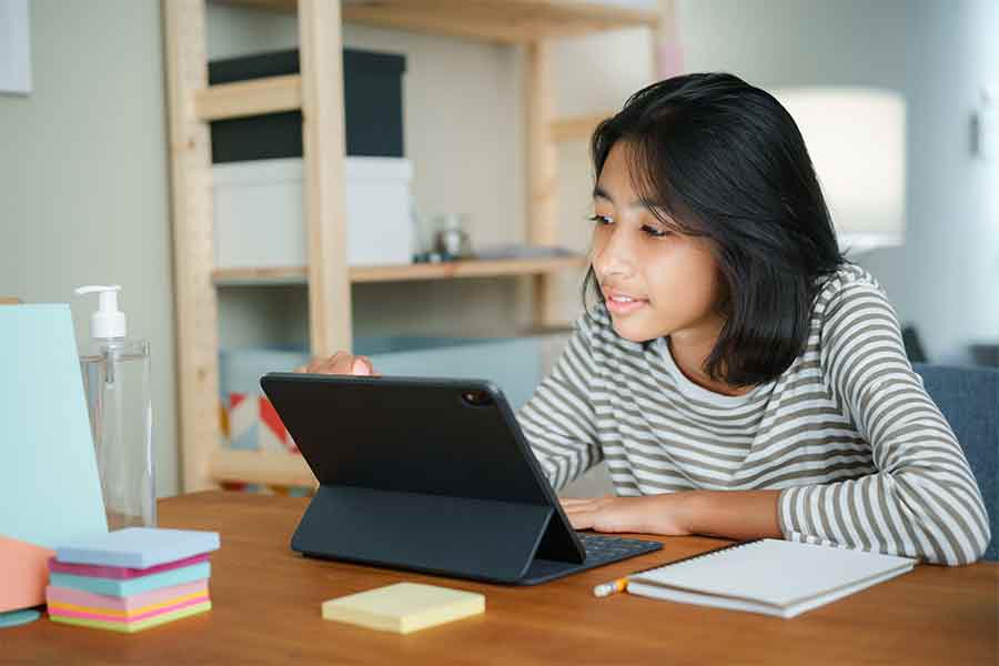 Teen girl sitting at a desk working on a tablet computer