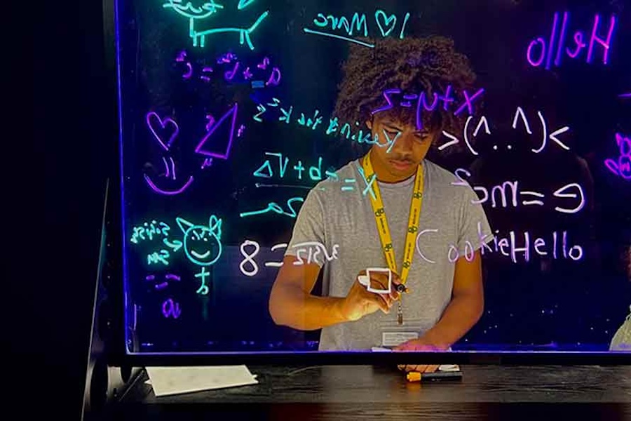 High school boy writing on a clear light board