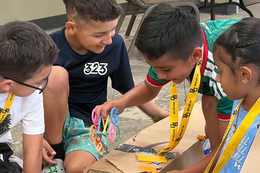 Group of young children working together on a project made with cardboard on the floor