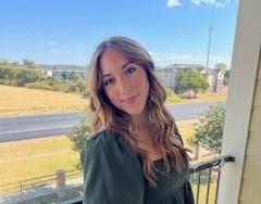 Taryn standing on a balcony in a green dress.