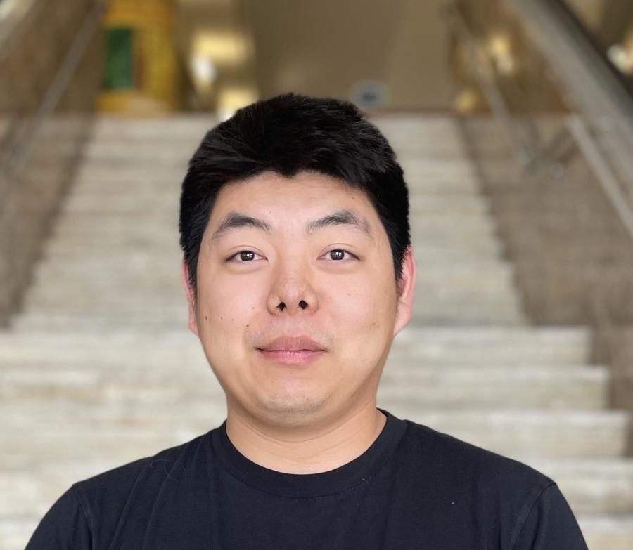 Jianwen is looking directly at the camera. He is wearing a black shirt and is cleanshaven.